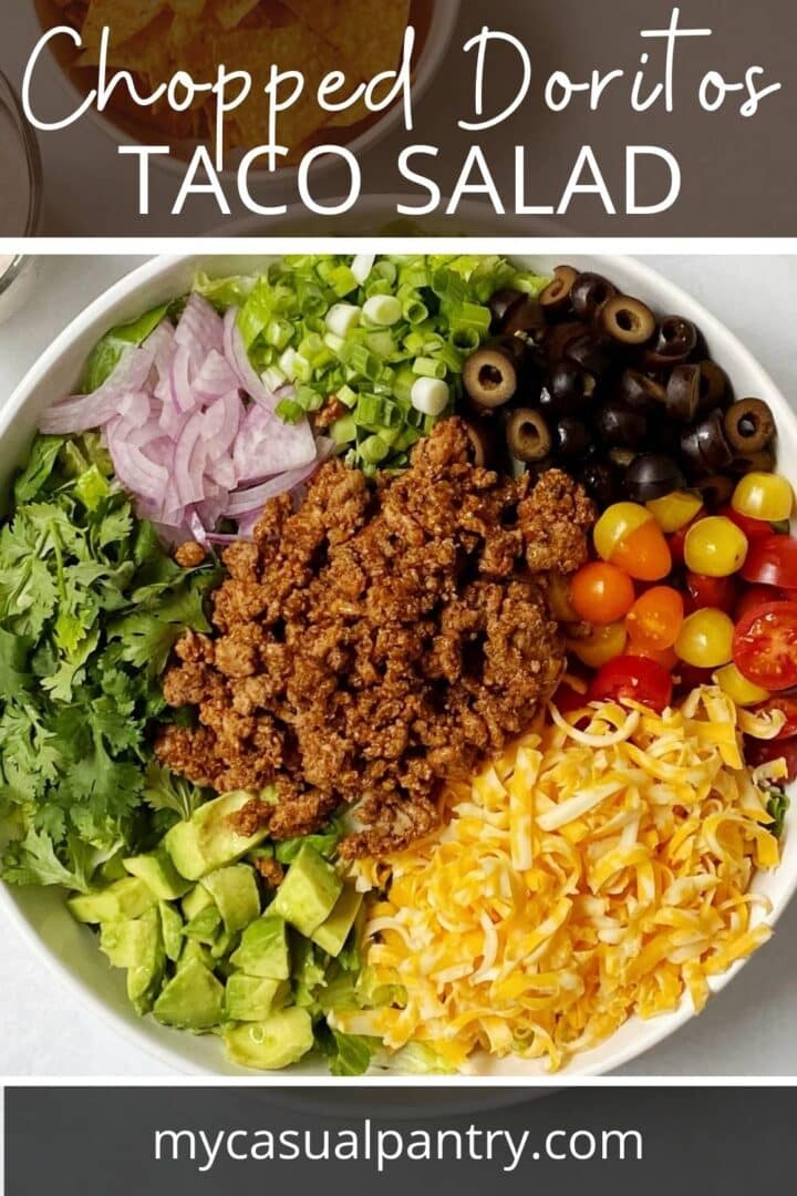 Serving bowl filled with lettuce and all of the taco salad components arranged in groups.