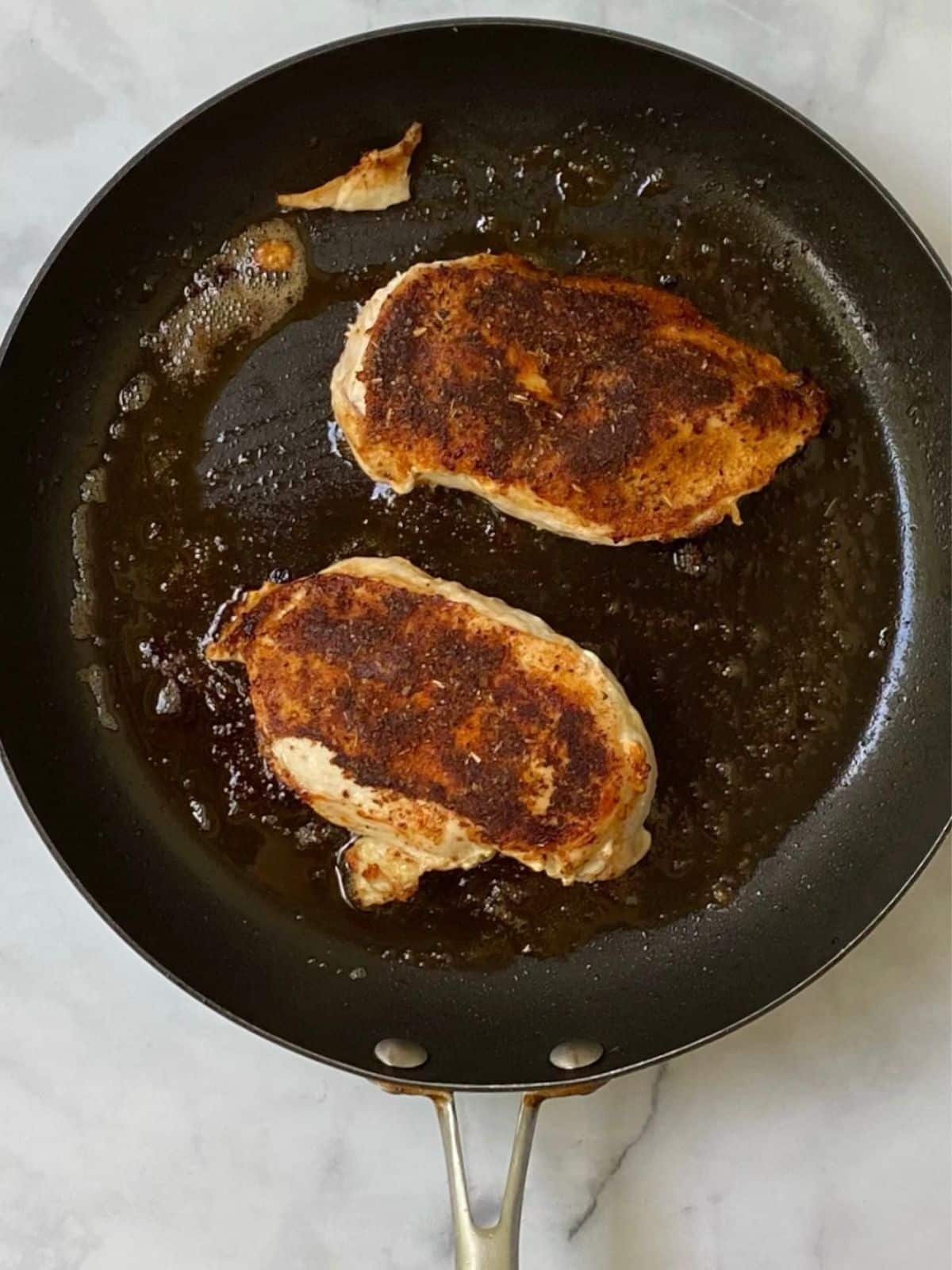 searing the chicken in a skillet.