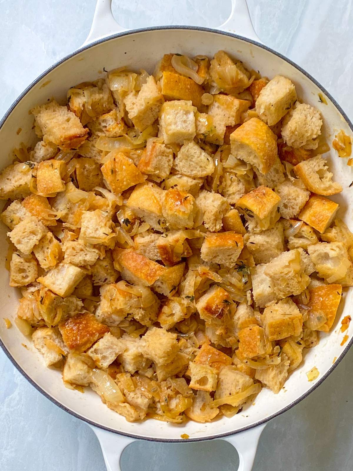 toasted bread cubes tossed in skillet with caramelized onions.
