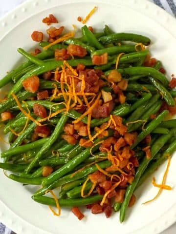 plate of roasted green beans topped with crispy pancetta and orange butter.