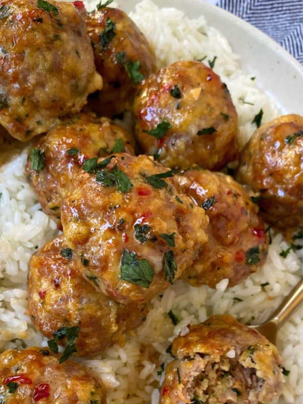 close up of meatballs with rice on a plate.