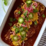 Casserole dish of baked salsa chicken topped with jalapenos, cilantro, and pickled red onions.