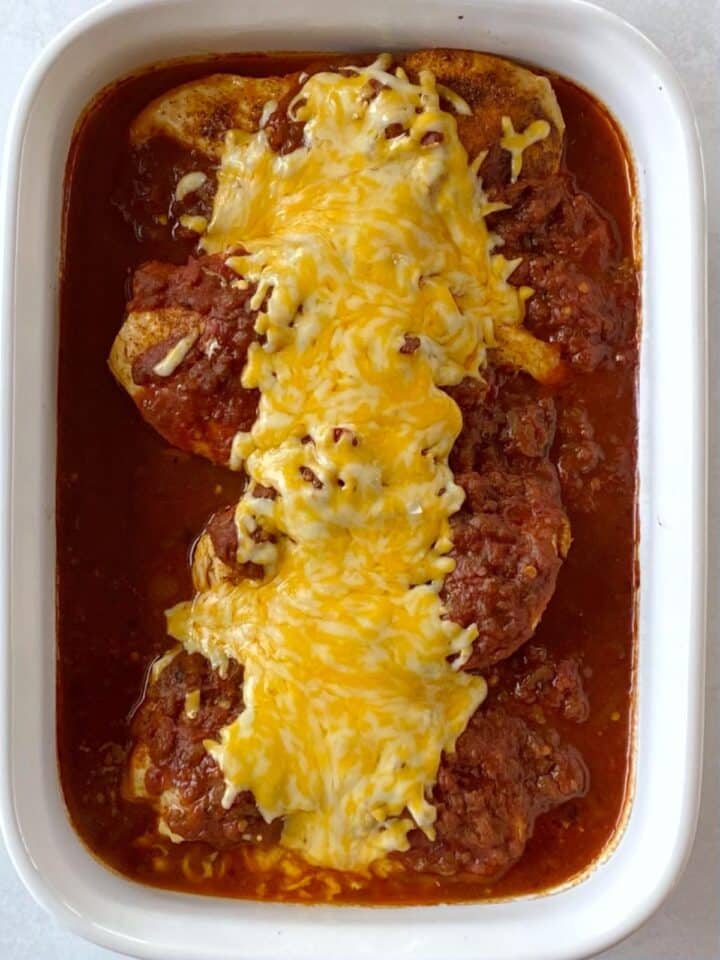 Salsa chicken in a casserole dish topped with melted cheese.