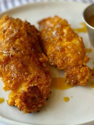 crispy chicken tenders coated with Cap'n Crunch cereal on a plate.