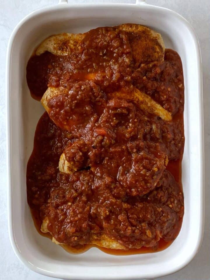 Seared chicken in a baking dish covered with salsa.