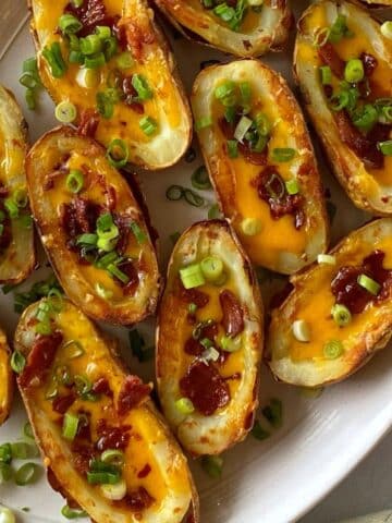 Cheesy baked potato skins with bacon on a platter.