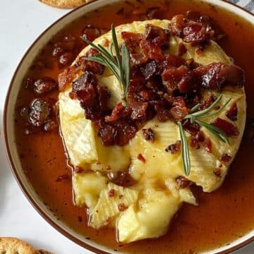 Baked brie on a platter topped with maple syrup and bacon.