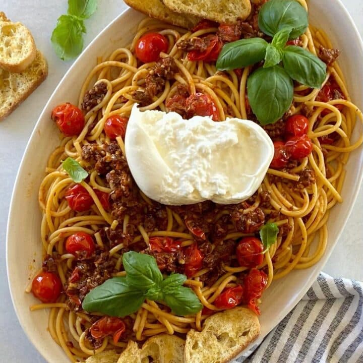 Oval serving platter with tomato bruschetta bucatini pasta.