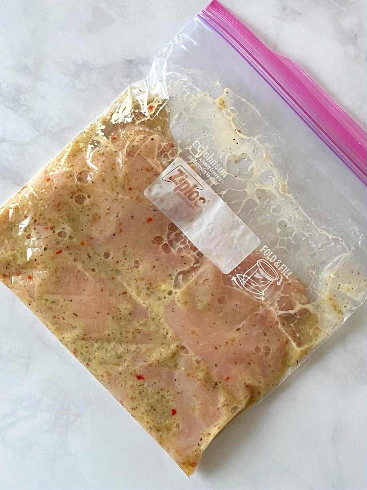 Chicken marinating in a zipper-top bag.