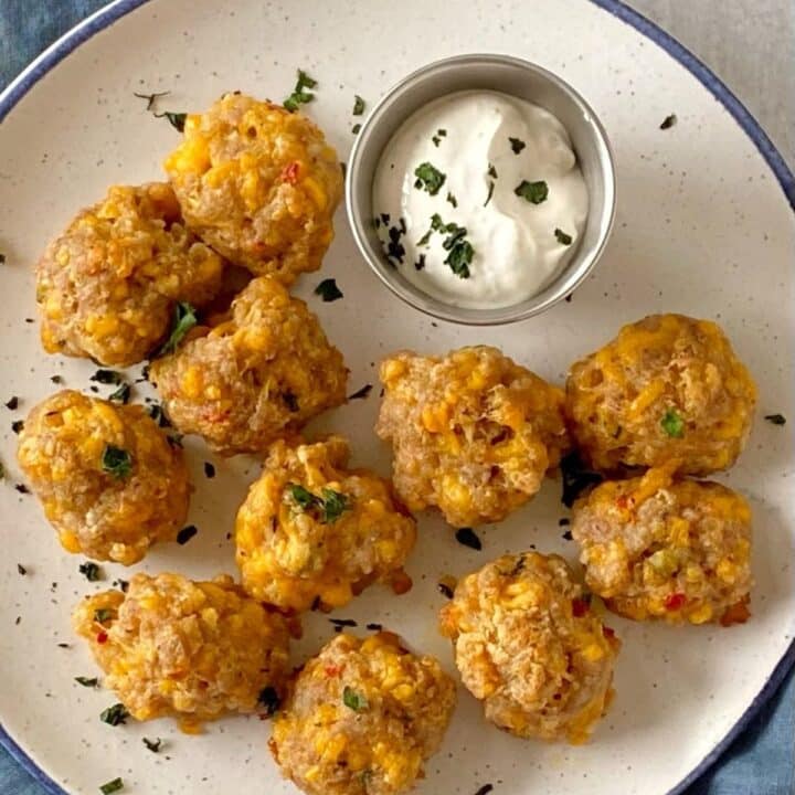 Baked sausage cheese balls with sauce on a plate.