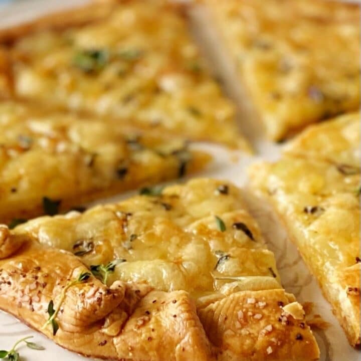 Sliced of golden brown potato tart topped with fresh thyme.