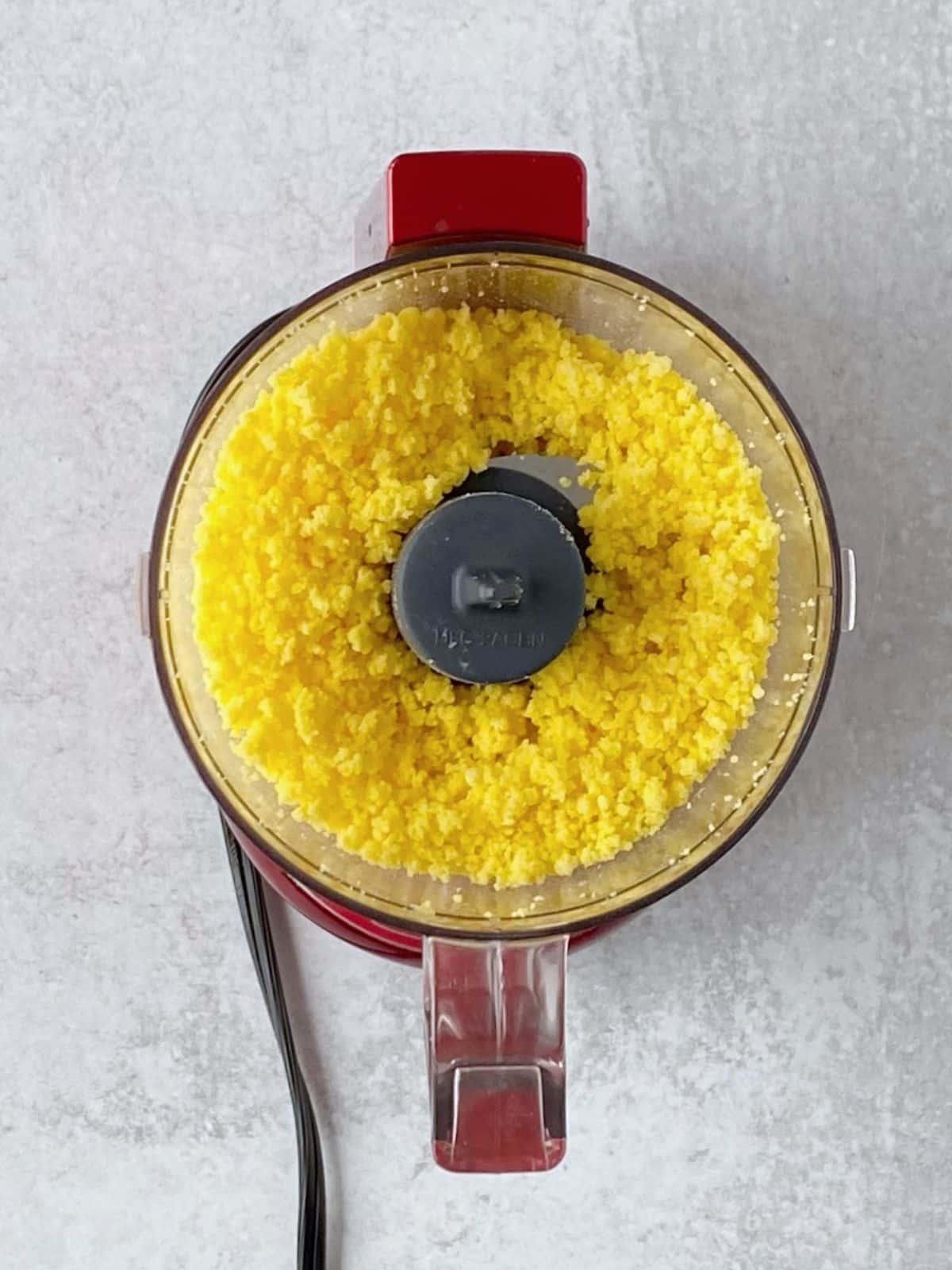 Chopped egg yolks in the bowl of a food processor.