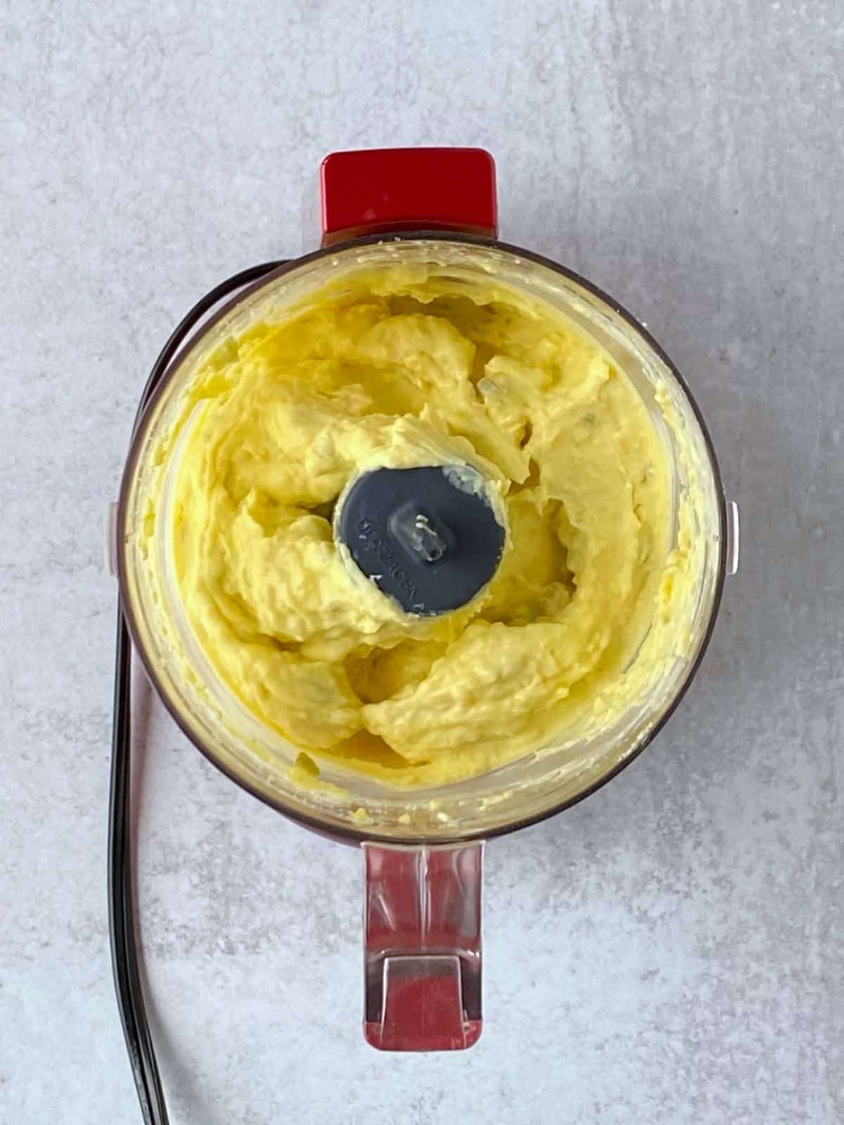 Deviled egg filling in the bowl of a food processor.