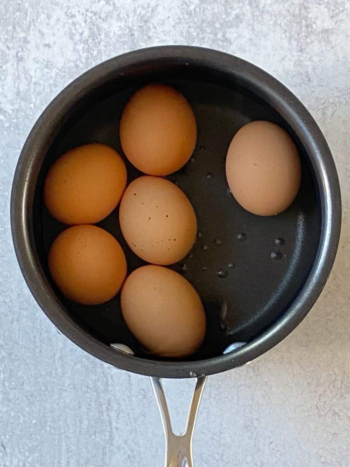 Eggs cooking in a saucepan of water.