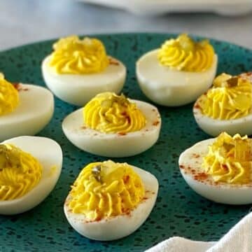 Deviled eggs garnished with paprika on a plate.