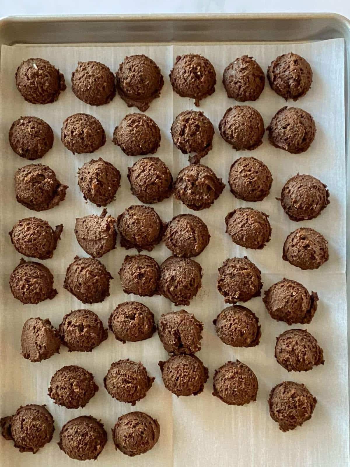 Cookie dough portioned into balls on a parchment-lined baking sheet.