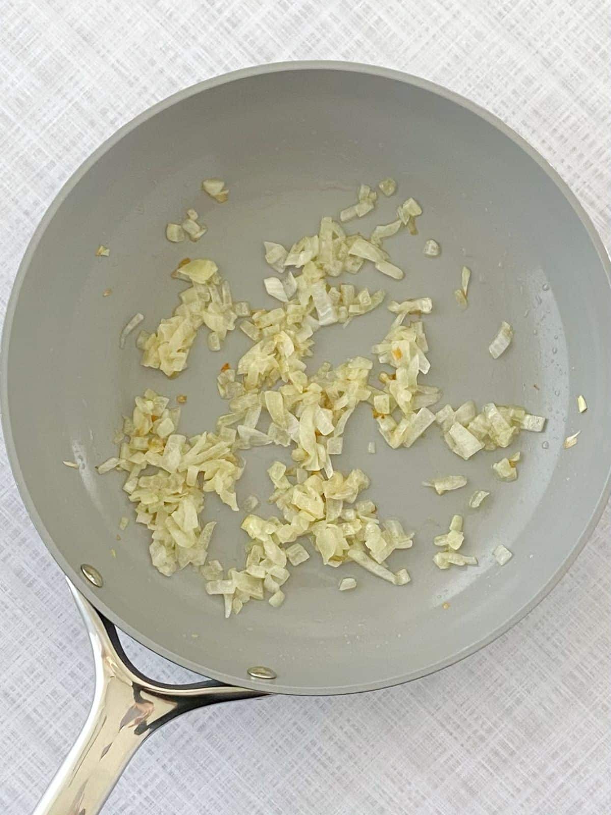 Cooking diced onions in buter in a skillet.