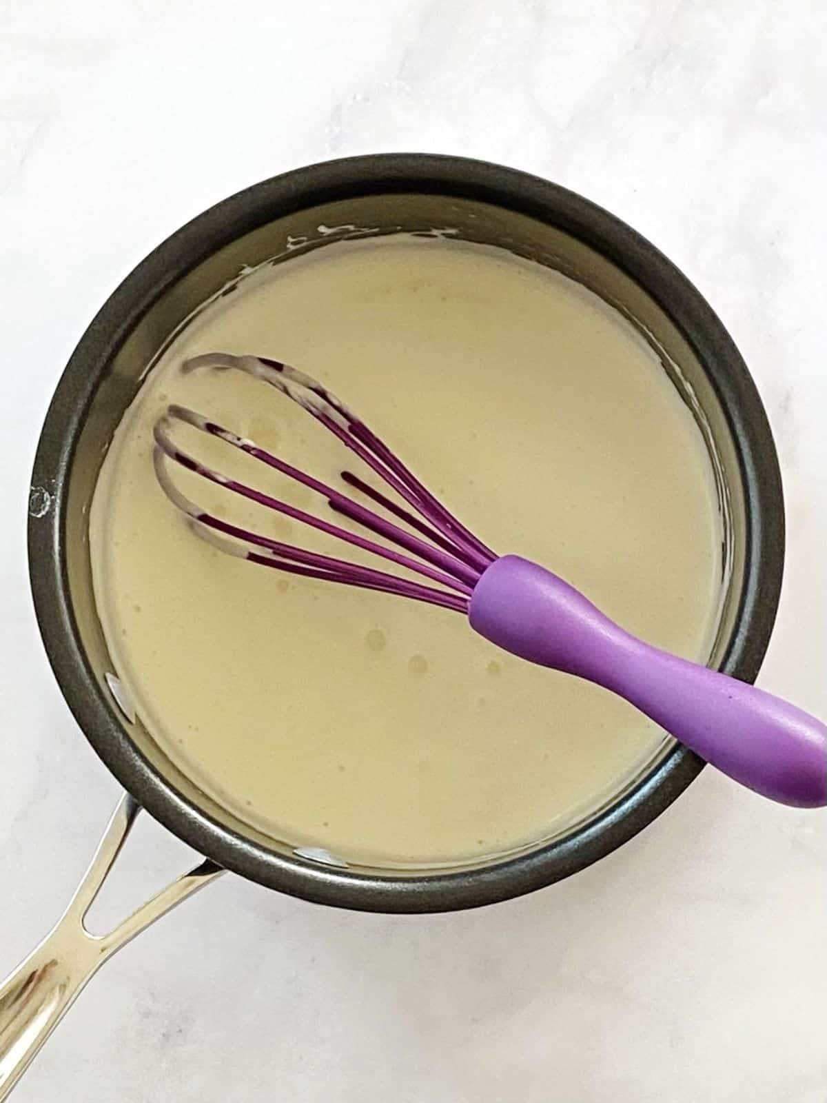 Milk and cream cheese mixture in a saucepan.