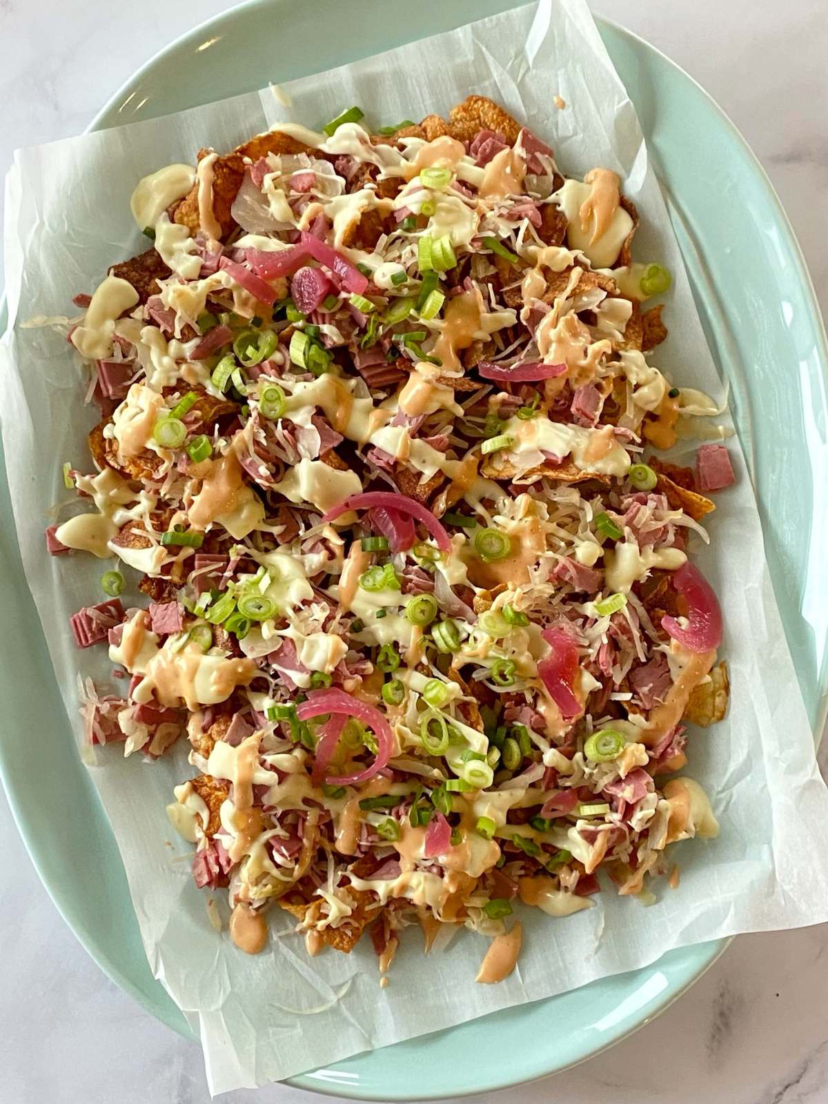 Platter of potato chips topped with corned beef, sauerkraut, cheese sauce, and dressing.