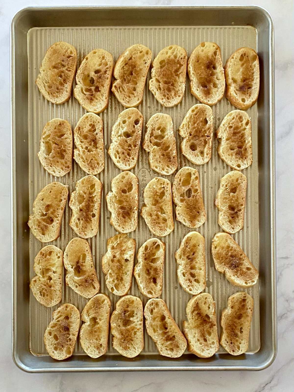 Toasted crostini on a sheet pan.
