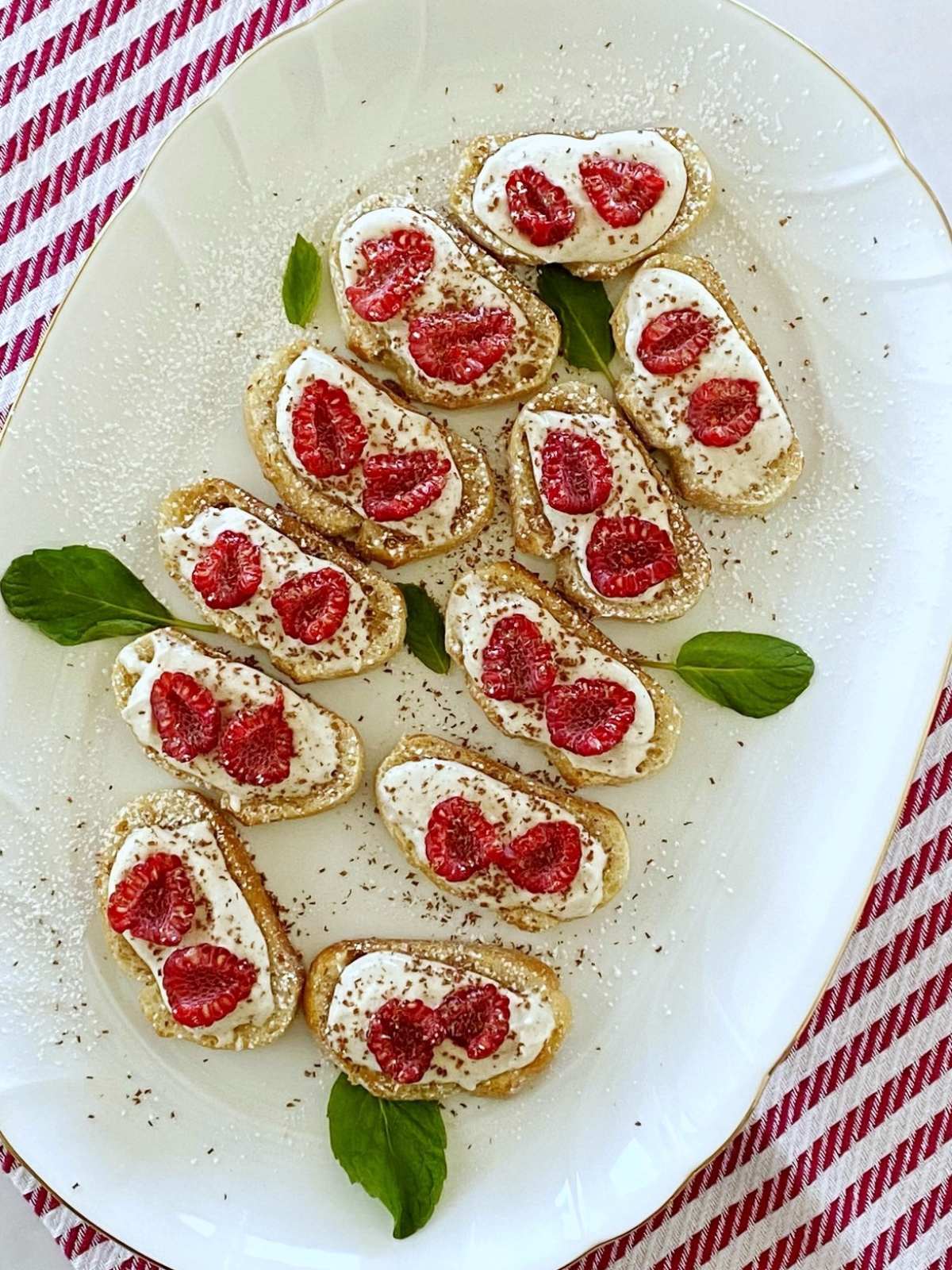 A serving platter of ricotta crostini garnished with shaved chocolate.