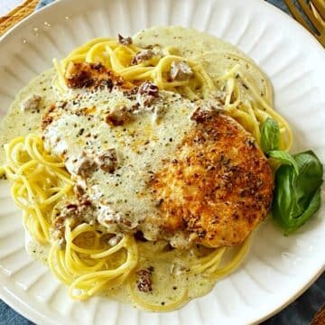 Chicken and sauce over pasta on a plate.