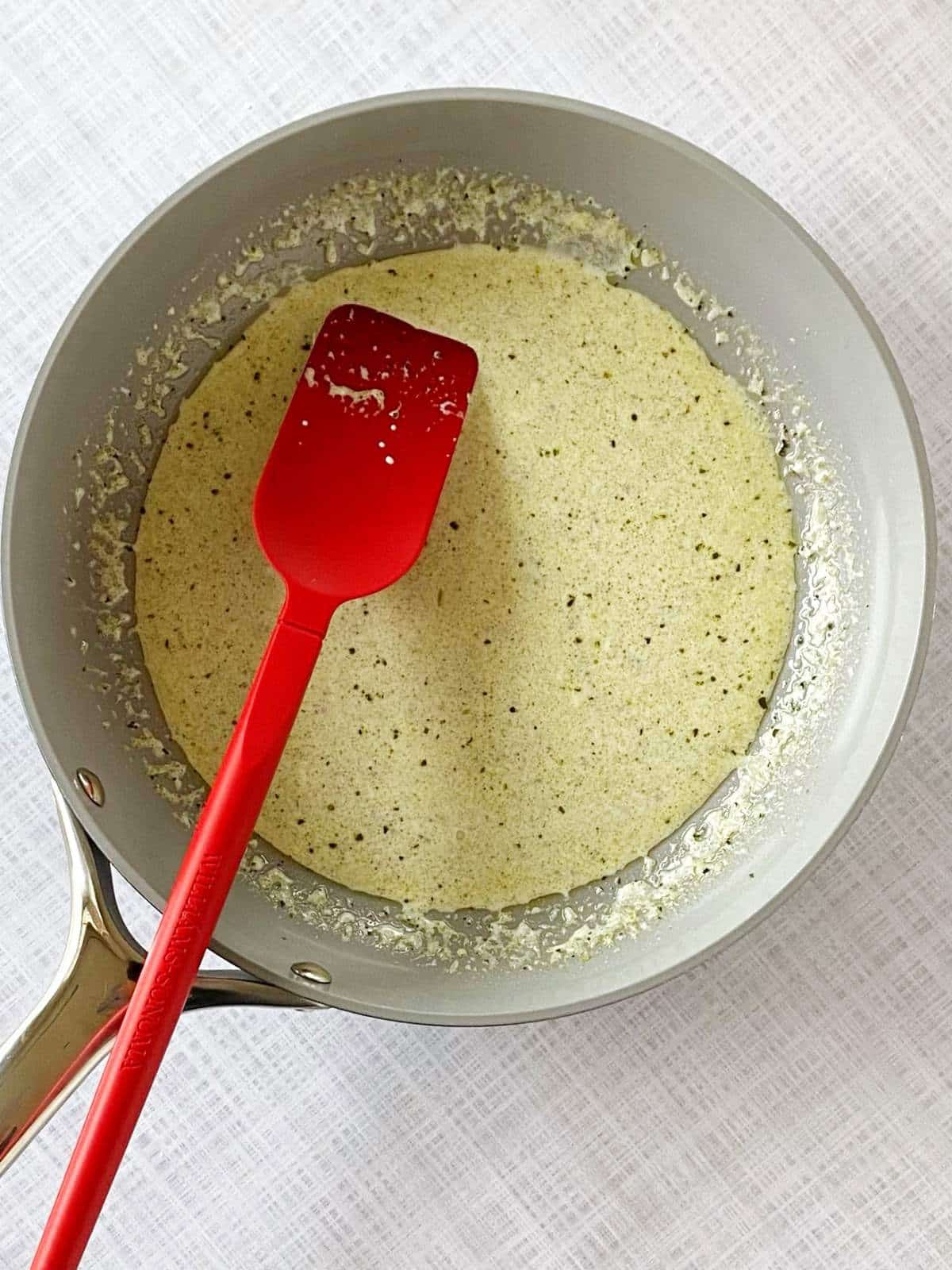 Half-and-half and pesto in a skillet.