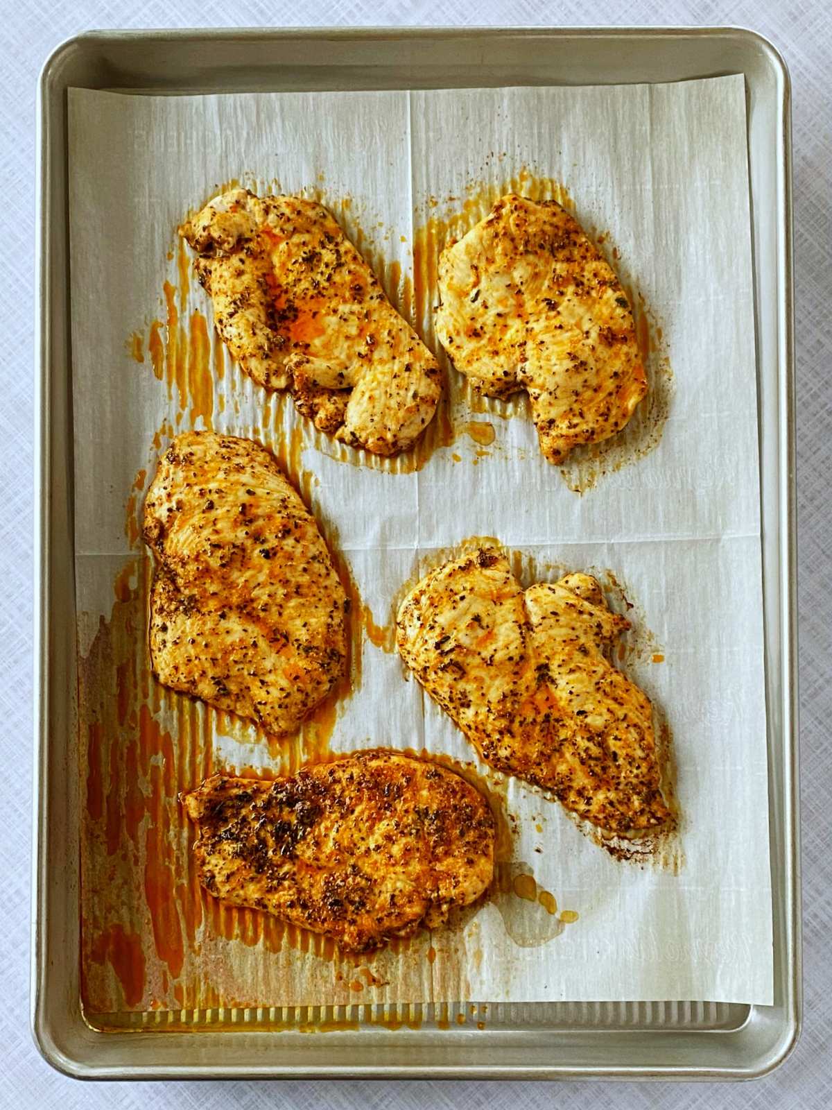 Baked chicken breasts on a sheet pan.