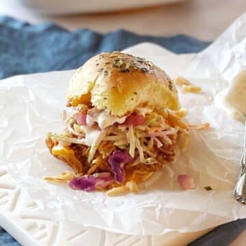 Chicken slider with toppings on a serving board.