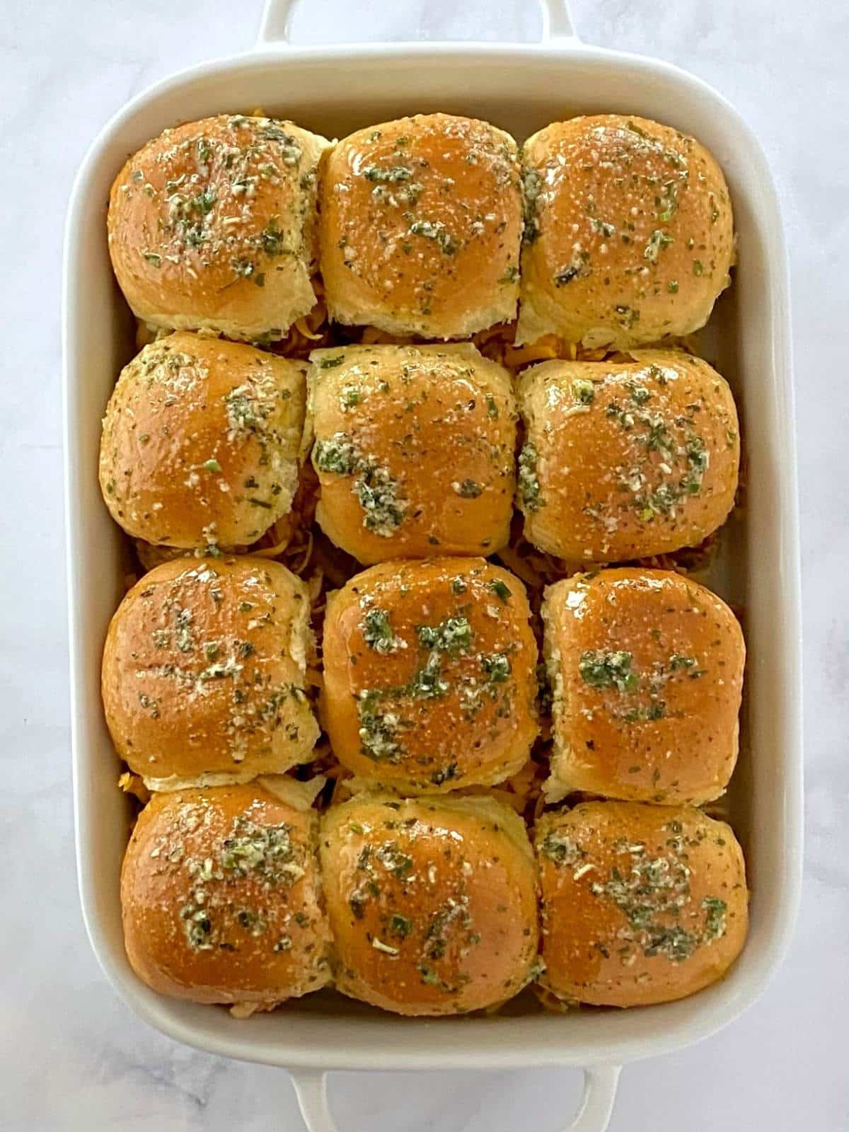 Baking dish of sliders brushed with melted butter mixture.