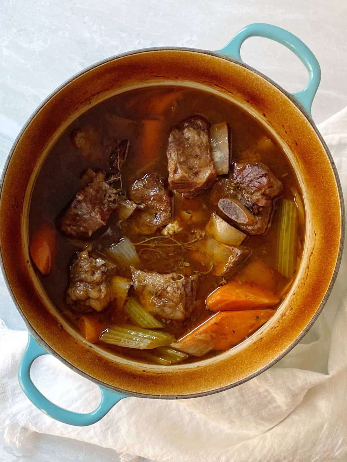 Cooked short ribs and vegetables in a Dutch oven.