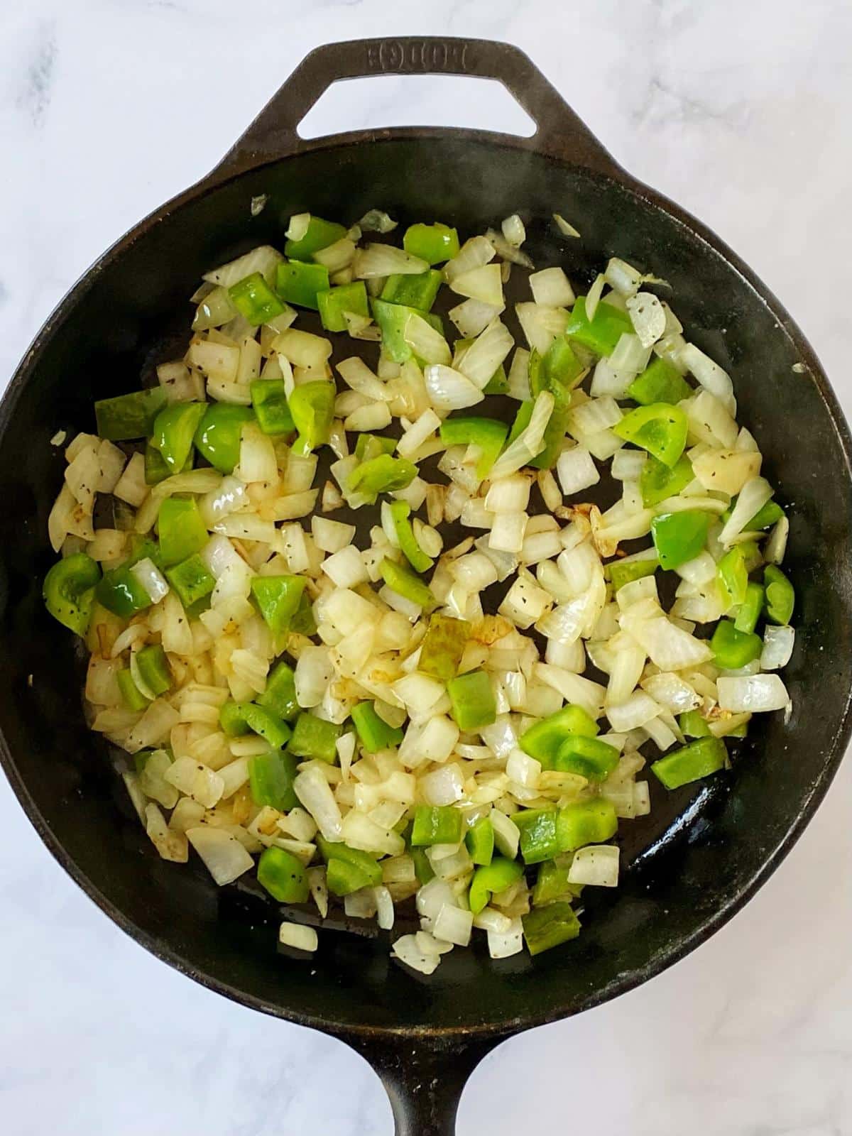 Green peppers and onions in a cast iron skillet.