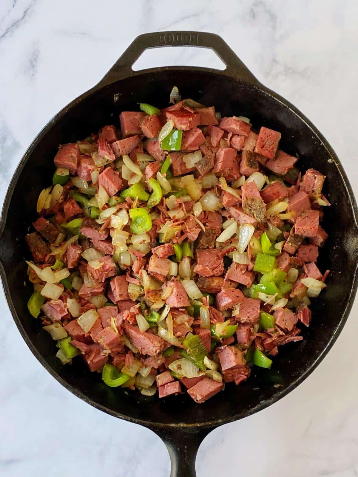 Corned beef, peppers, and onions in a skillet.