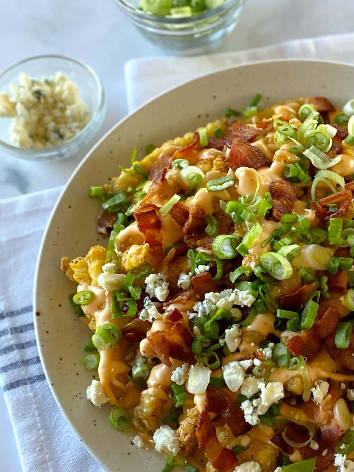 Loaded fries topped with blue cheese crumbles on a plate.