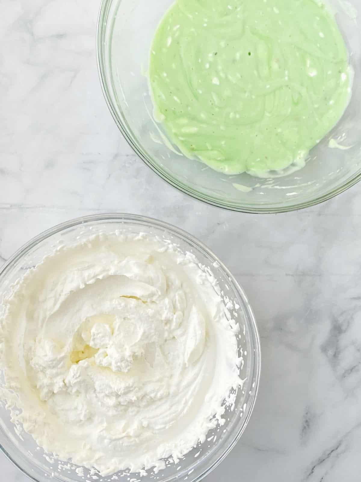 Pudding mixture and whipped cream in mixing bowls.