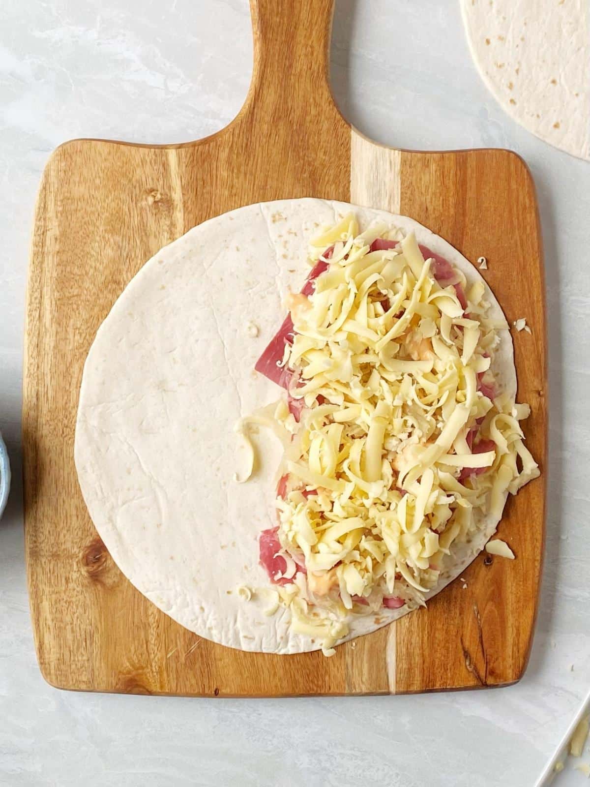 Tortilla topped with cheese, corned beef, sauerkraut, dressing, and more cheese.
