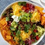 A serving bowl of taco sald with Doritos and all of the fixings.