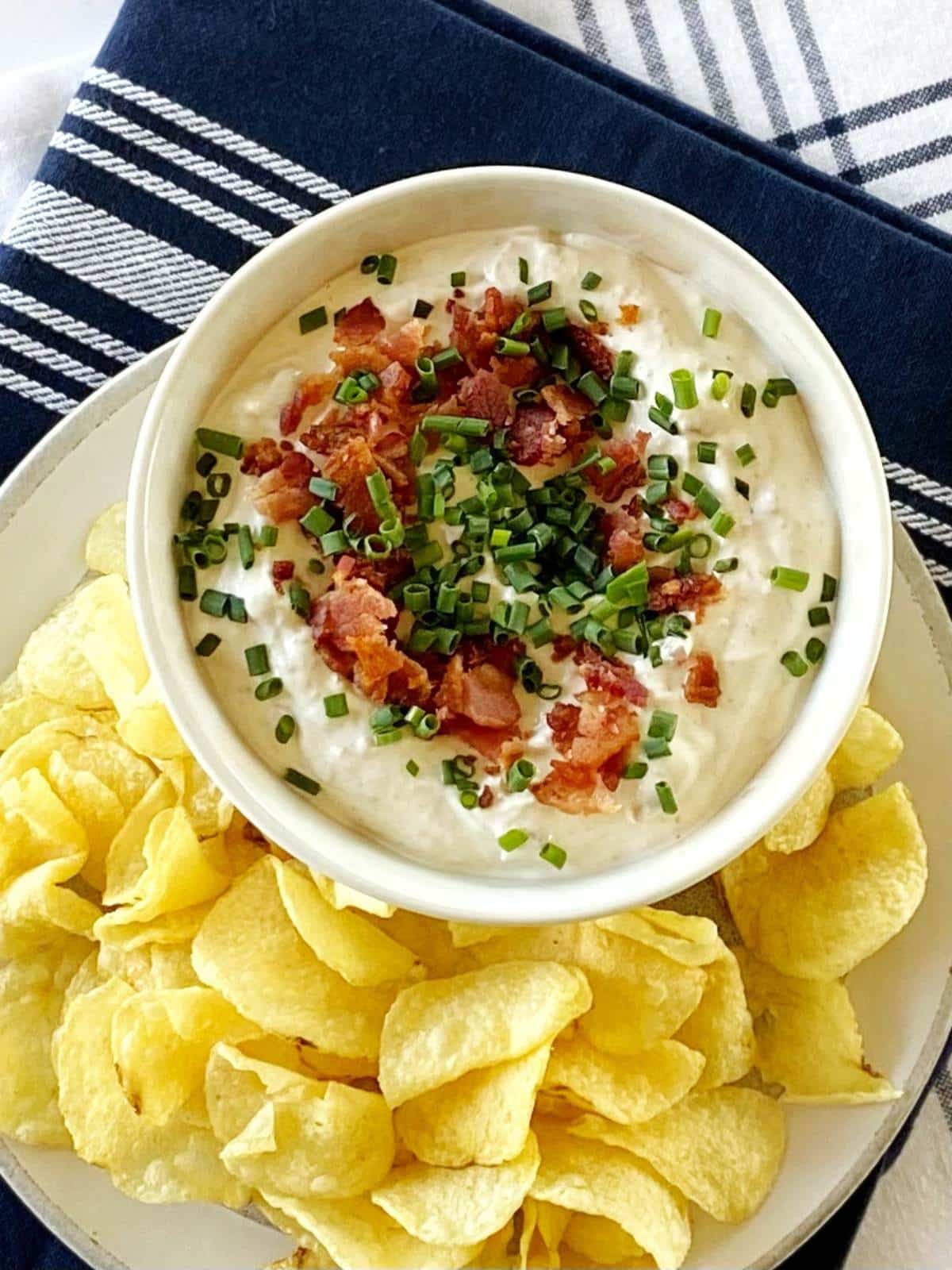 Plate of chips next to a bowl of dip.
