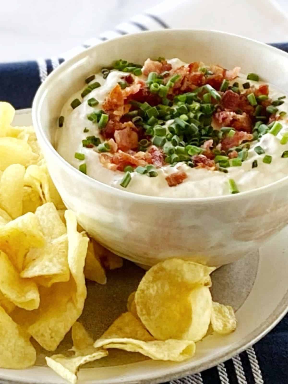 Chips on a plate next to a bowl of dip.