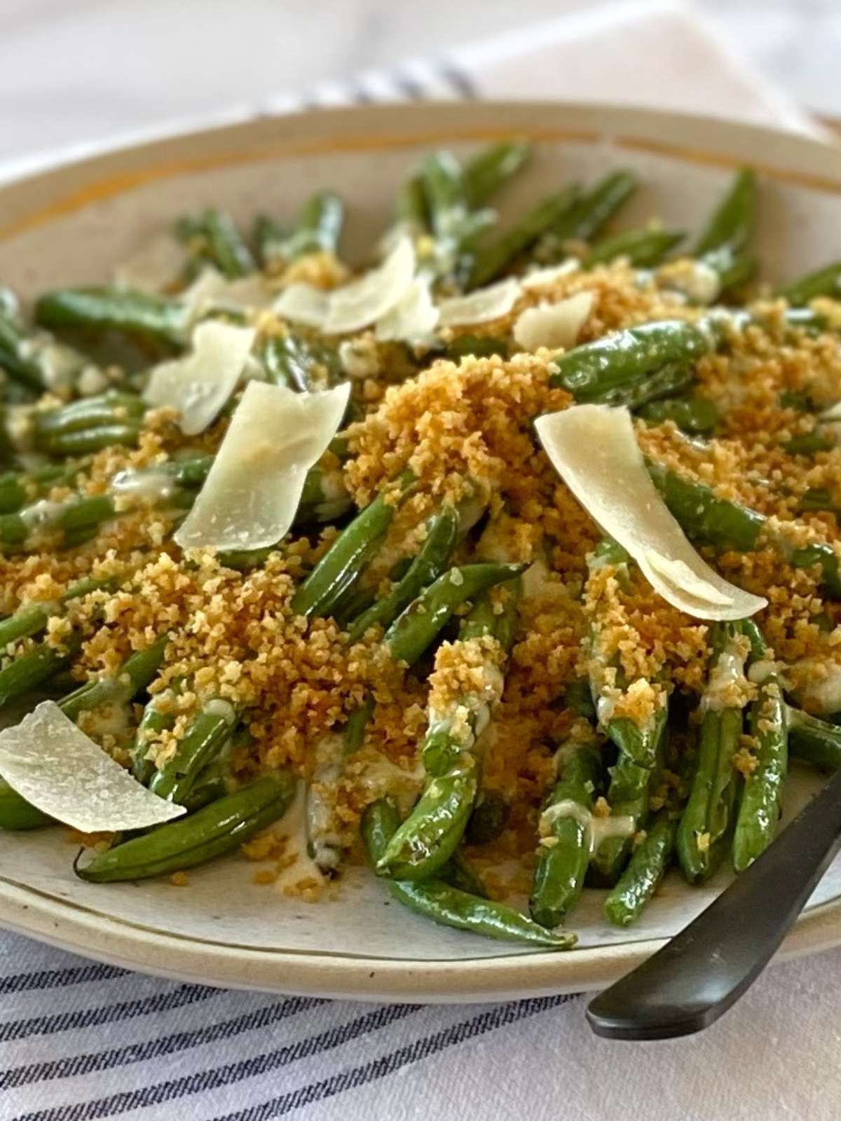 A platter of green beans garnished with Parmesan and breadcrumbs.