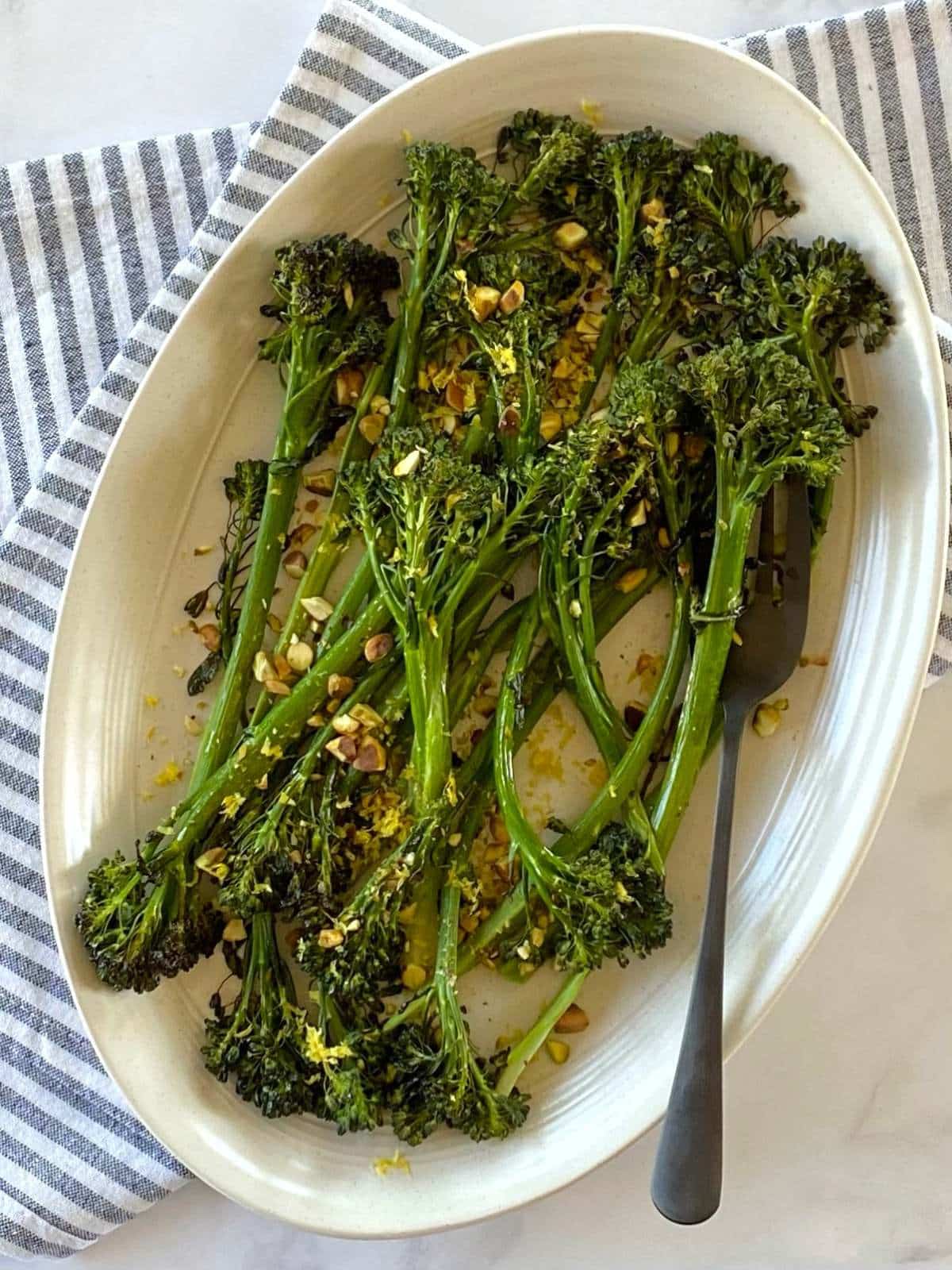 Pistachios and broccolini on a serving platter.