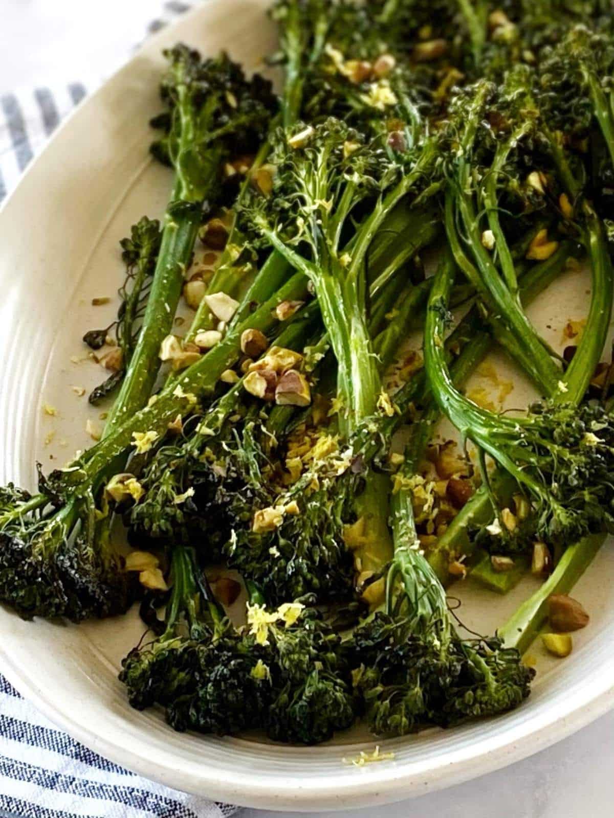Charred broccolini topped with pistachios on a platter.