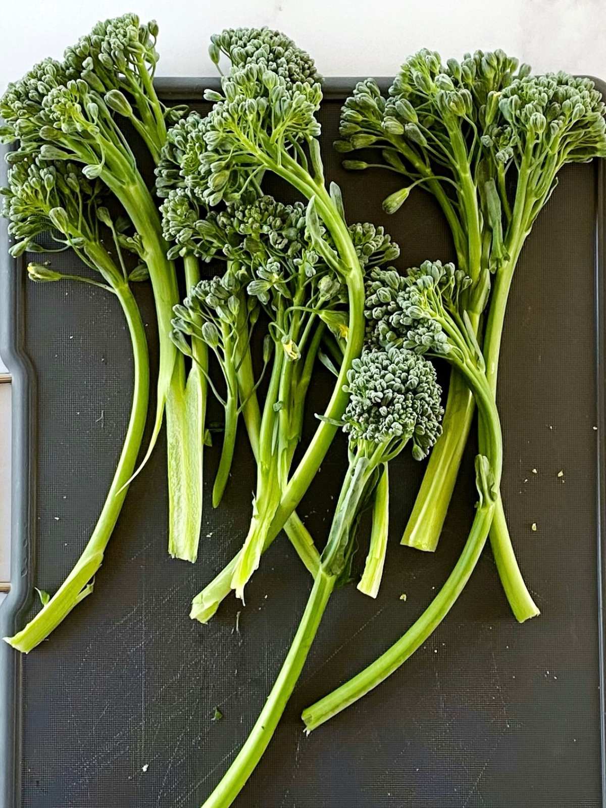 Trimming broccolini on a cutting board.
