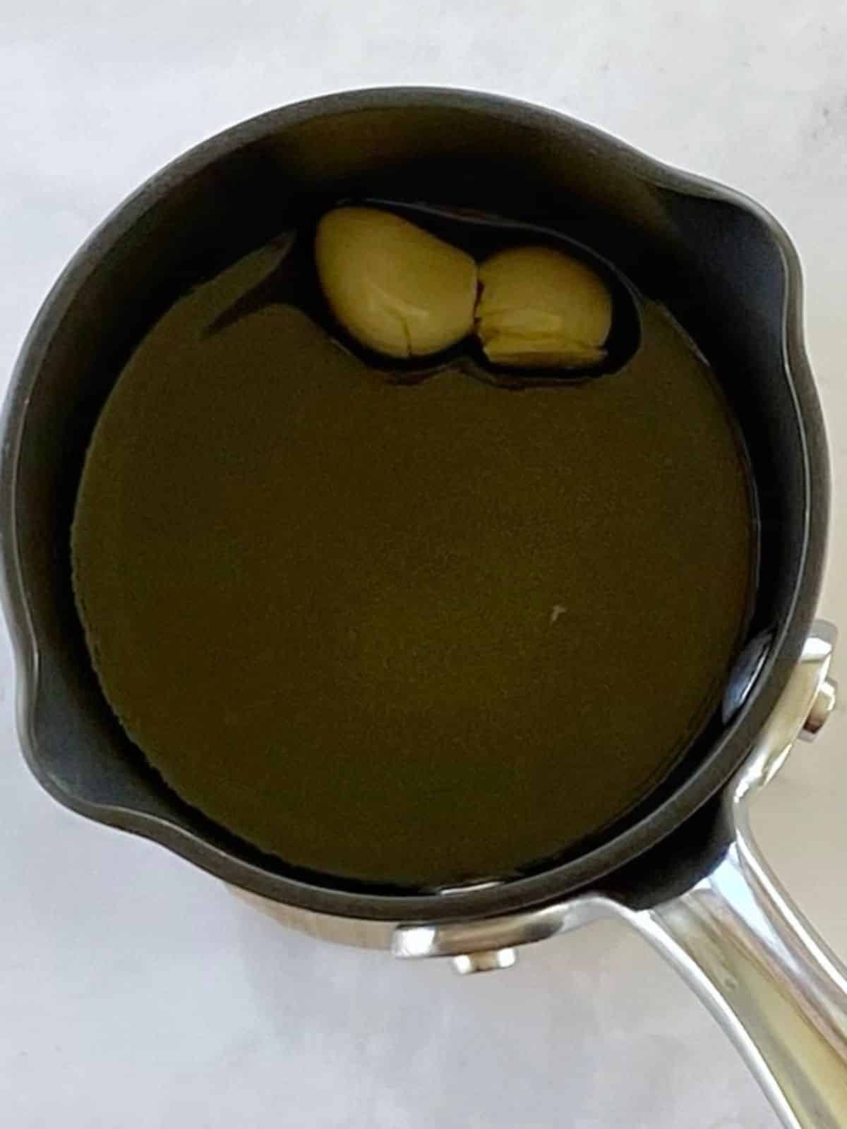 Garlic cloves with oil in a small saucepan.