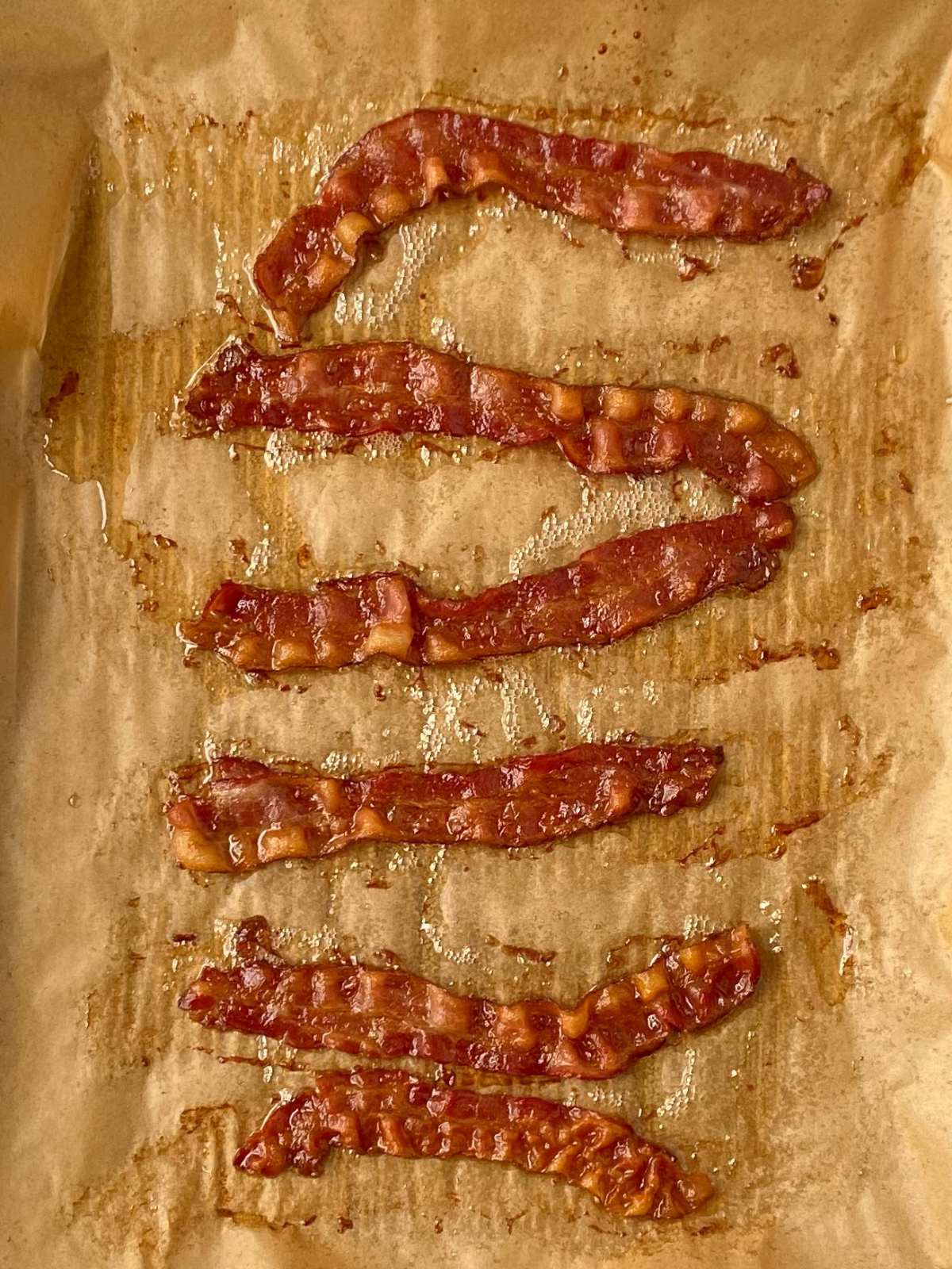 Cooked bacon on a parchment-lined sheet pan.