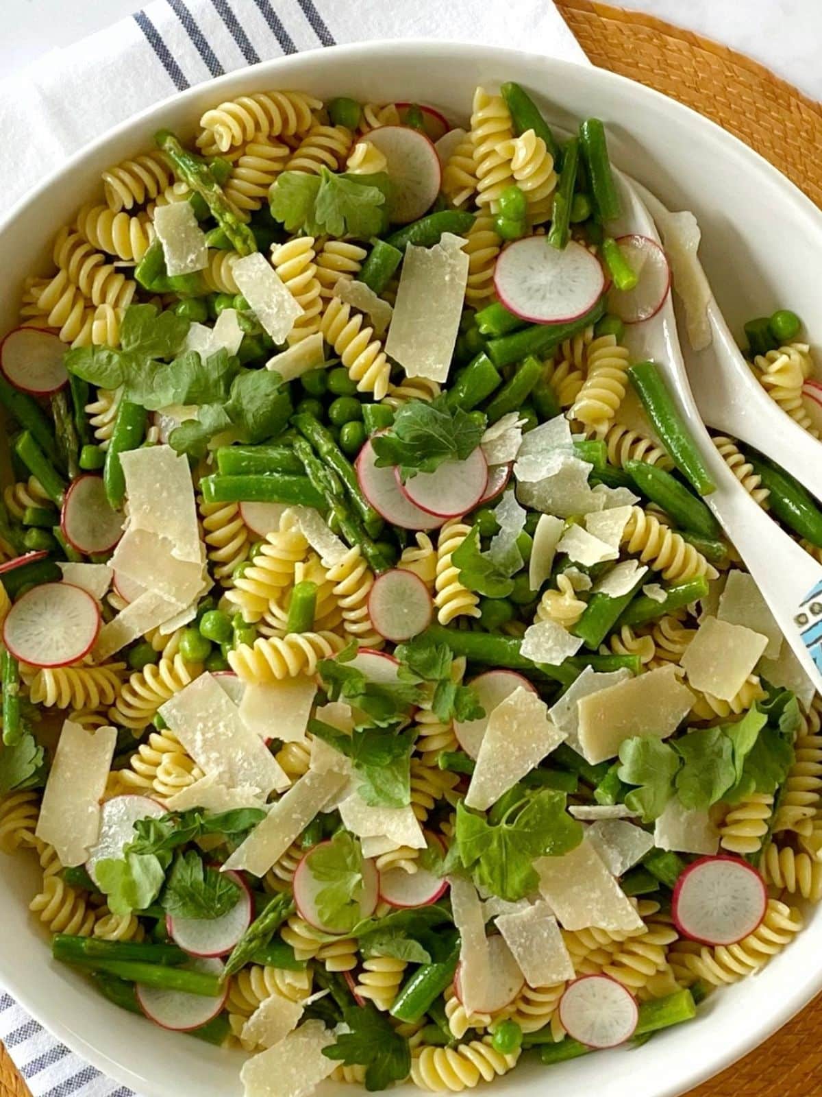 Pasta salad in a bowl with serving utensils.