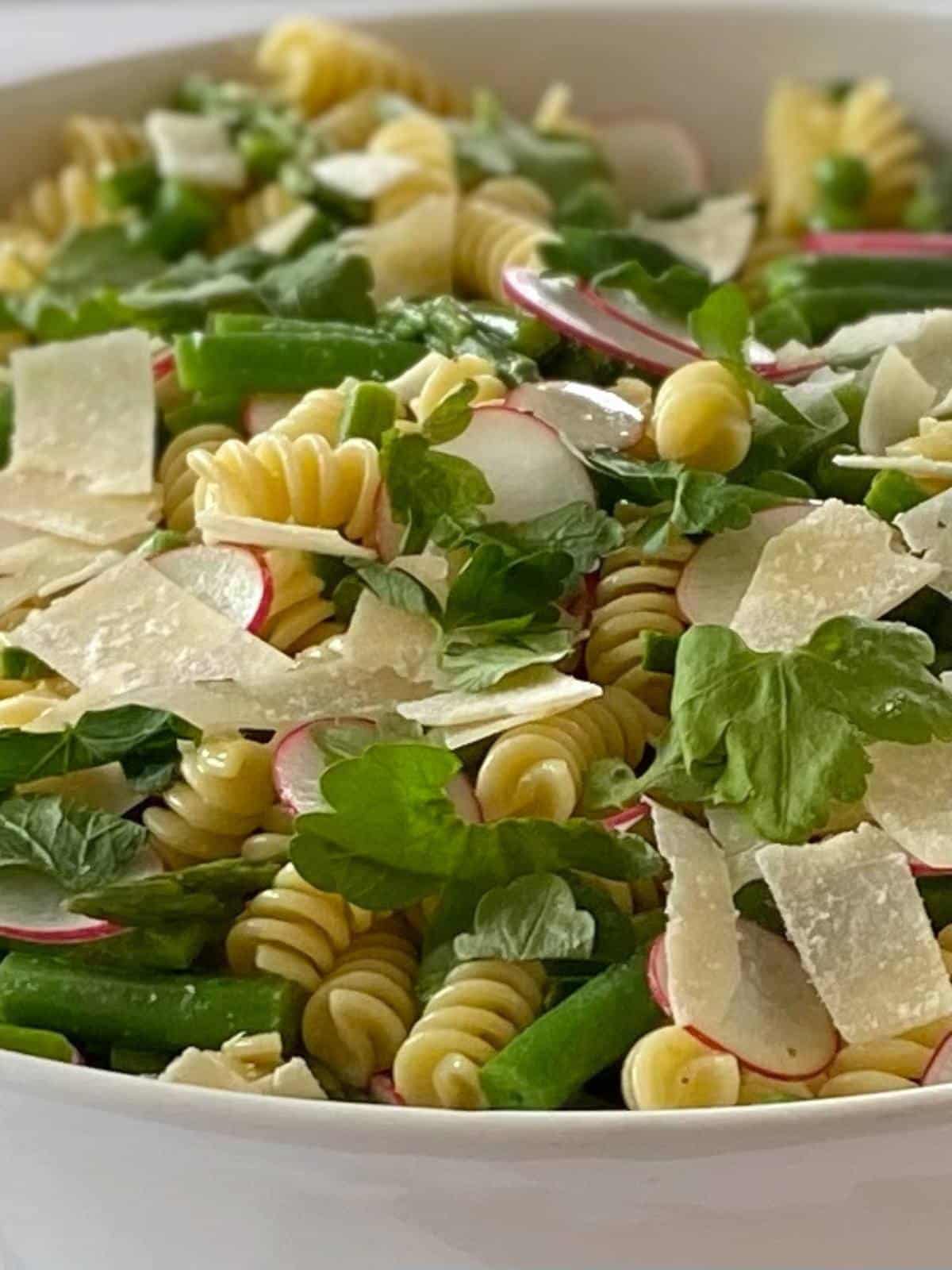 Pasta salad garnished with Parmesan shavings and parsley.