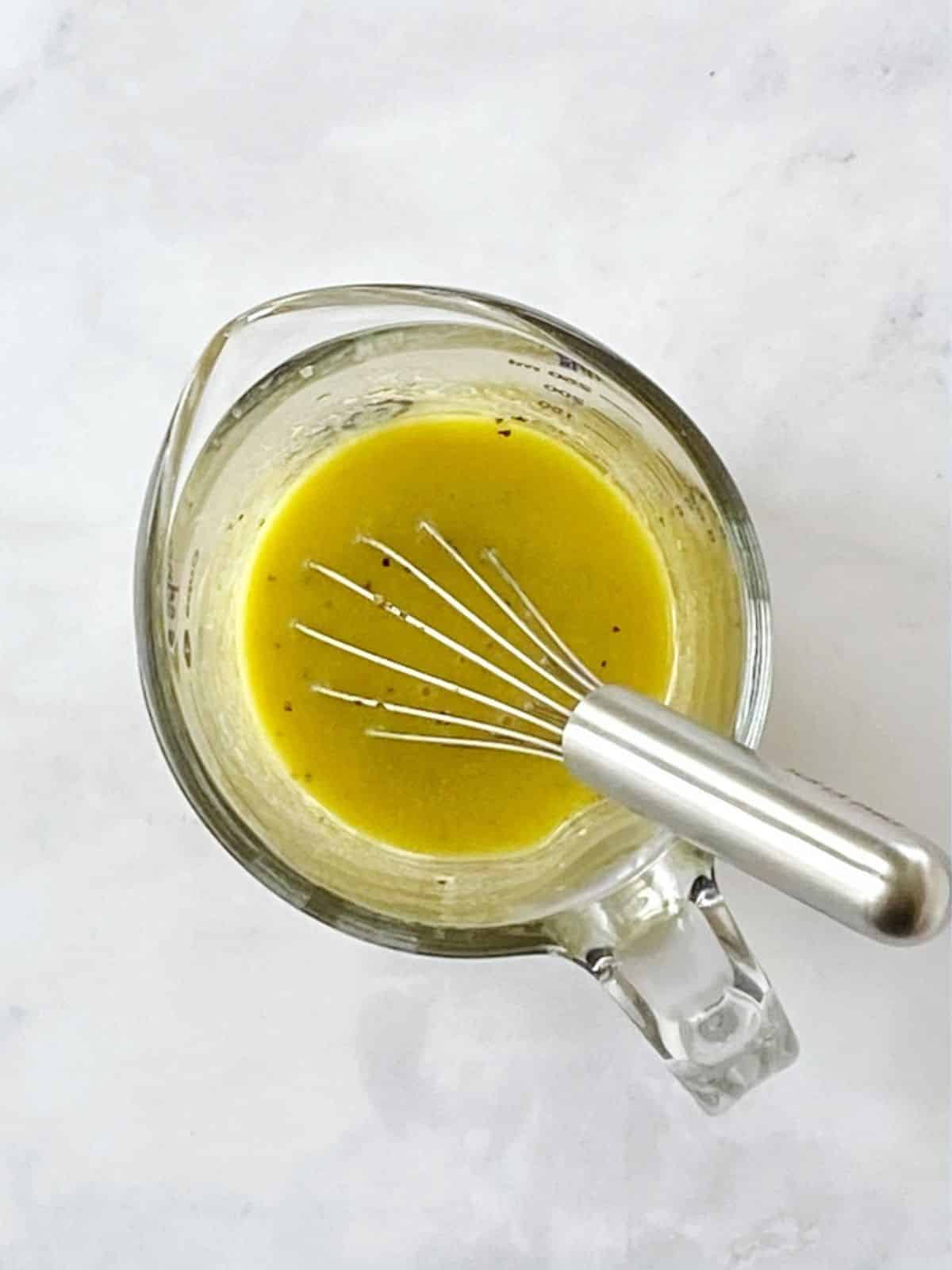 Glass pitcher of lemon mustard dressing.