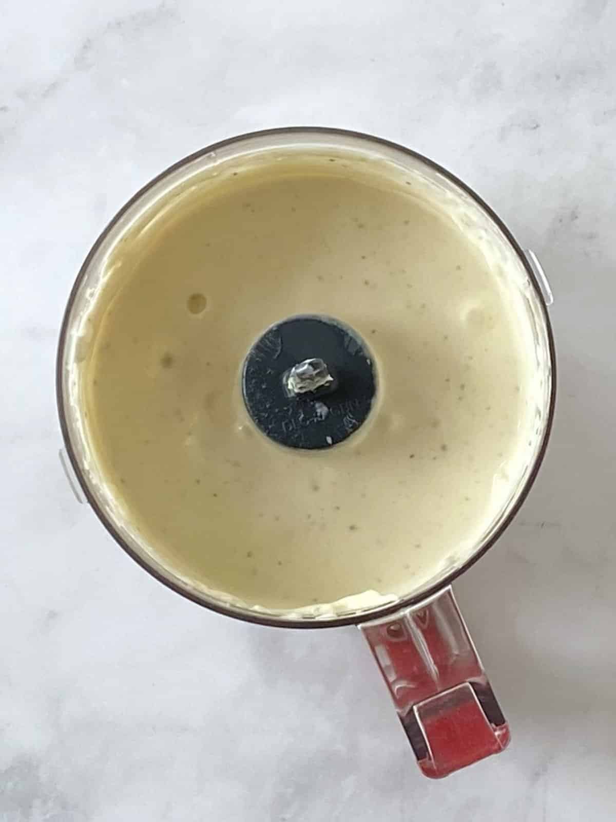 Blue cheese dressing in the bowl of a food processor.