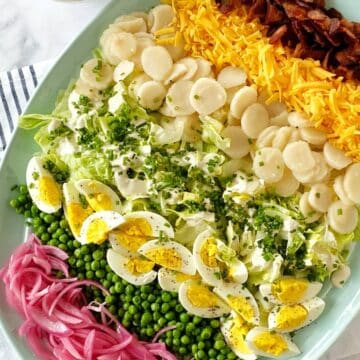 Salad ingredients layered on a platter and garnished with chopped chives.